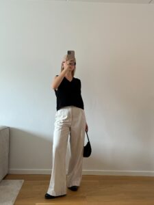 Black sweater vest with cream trousers and loafers